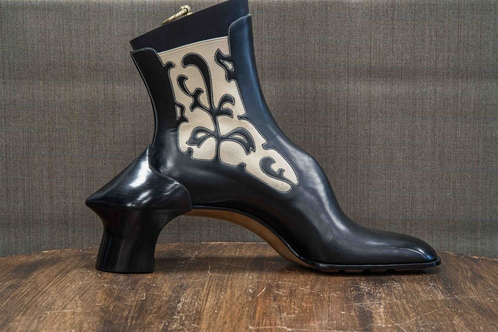 A black and cream ankle boot with a sculptural heel and intricate cut-out designs.