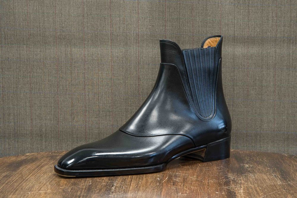 A sleek black leather ankle boot with a pointed toe and elastic side panels.