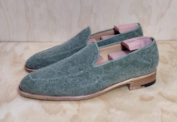 Green canvas loafers with a wooden shoe tree inside.