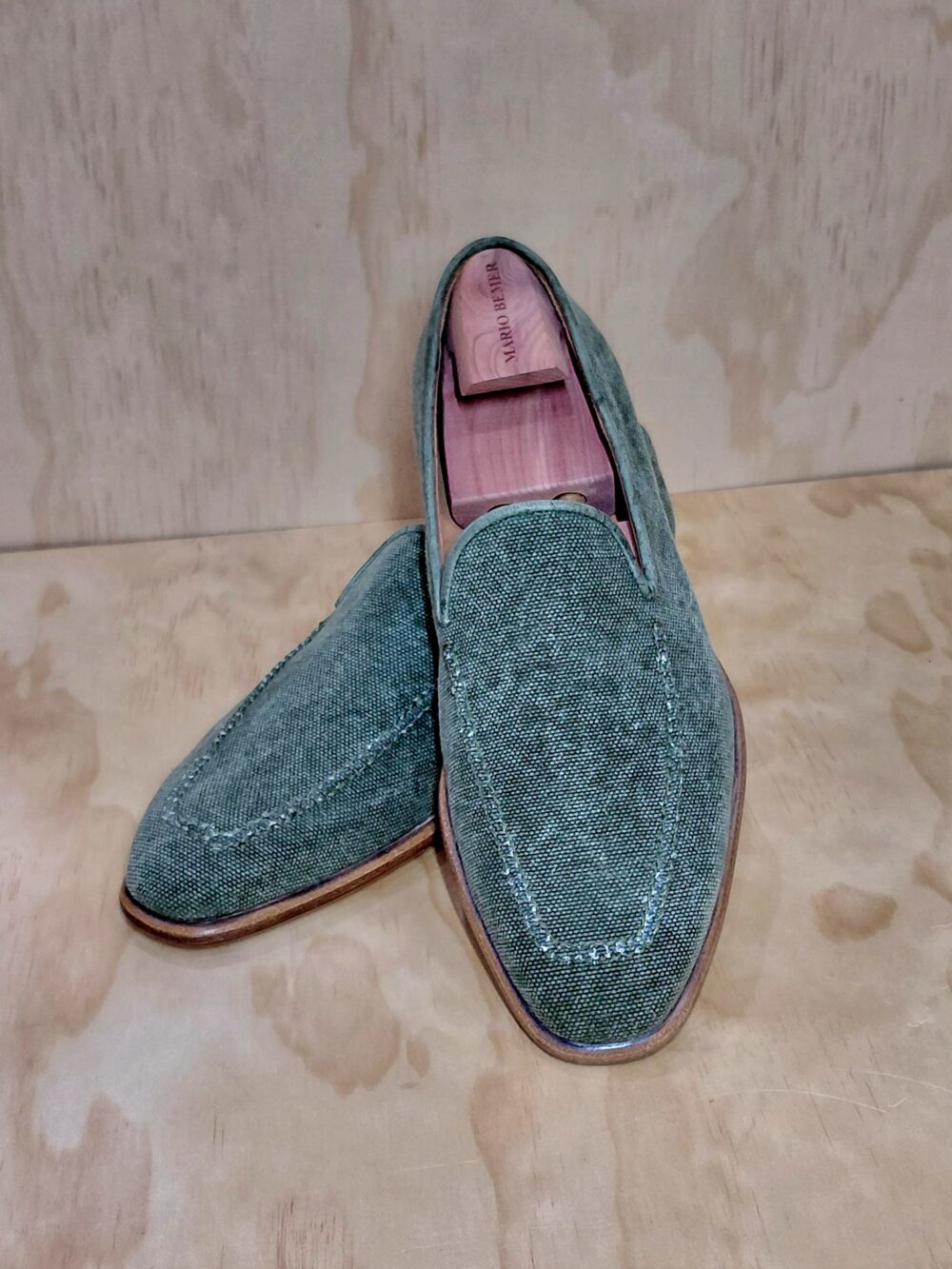 Mario Bemer canvas loafers in a textured green fabric with a brown sole.