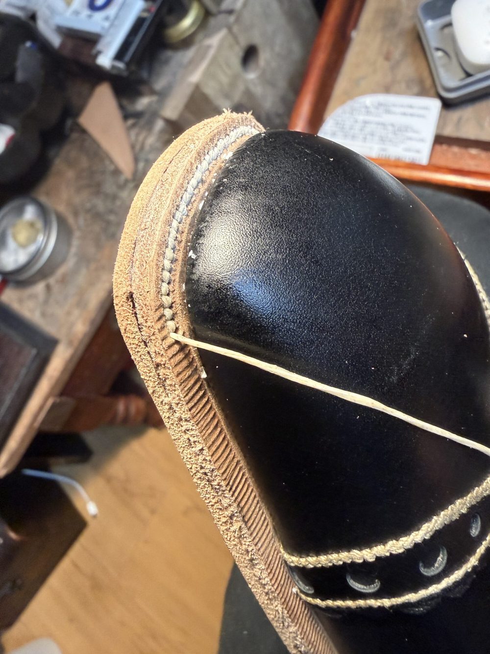Close-up of a black leather shoe's toe with a tan leather welt and a visible stitching detail.