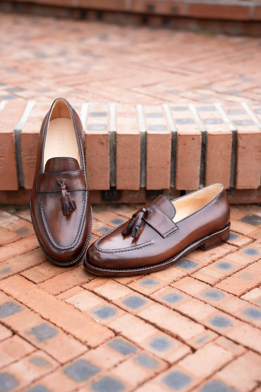 Brown cordovan loafers with tassels and a smooth finish.