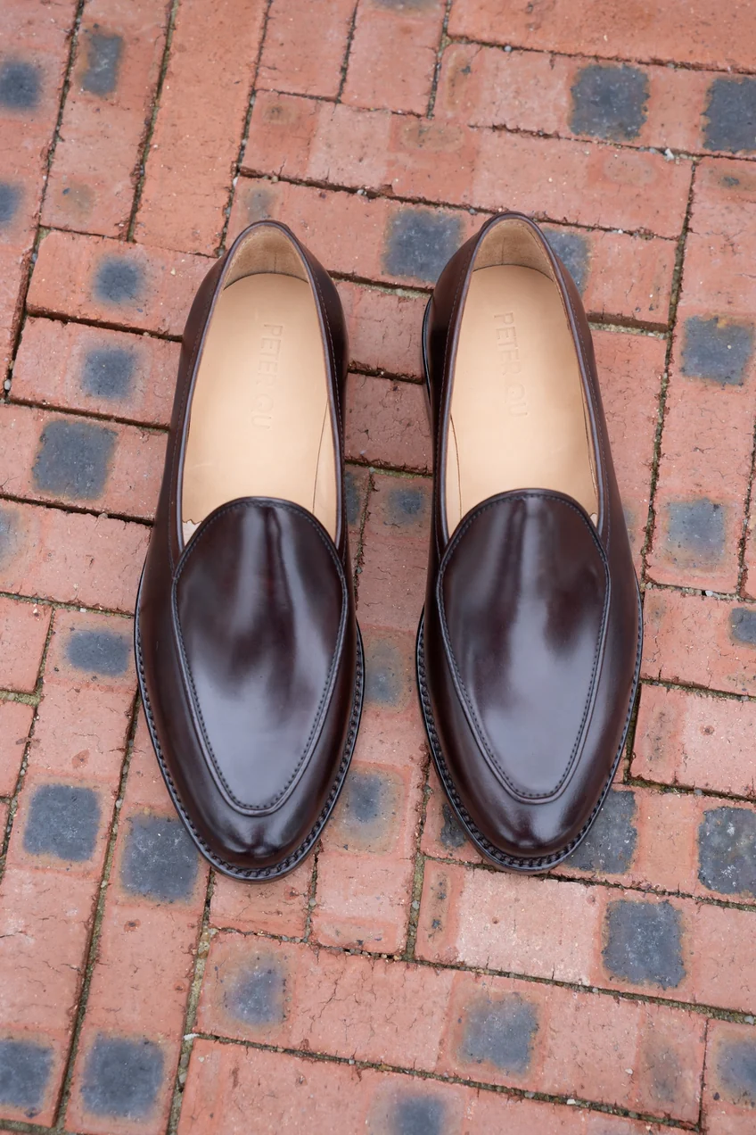 A pair of polished dark brown cordovan shoes with a sleek, rounded design.