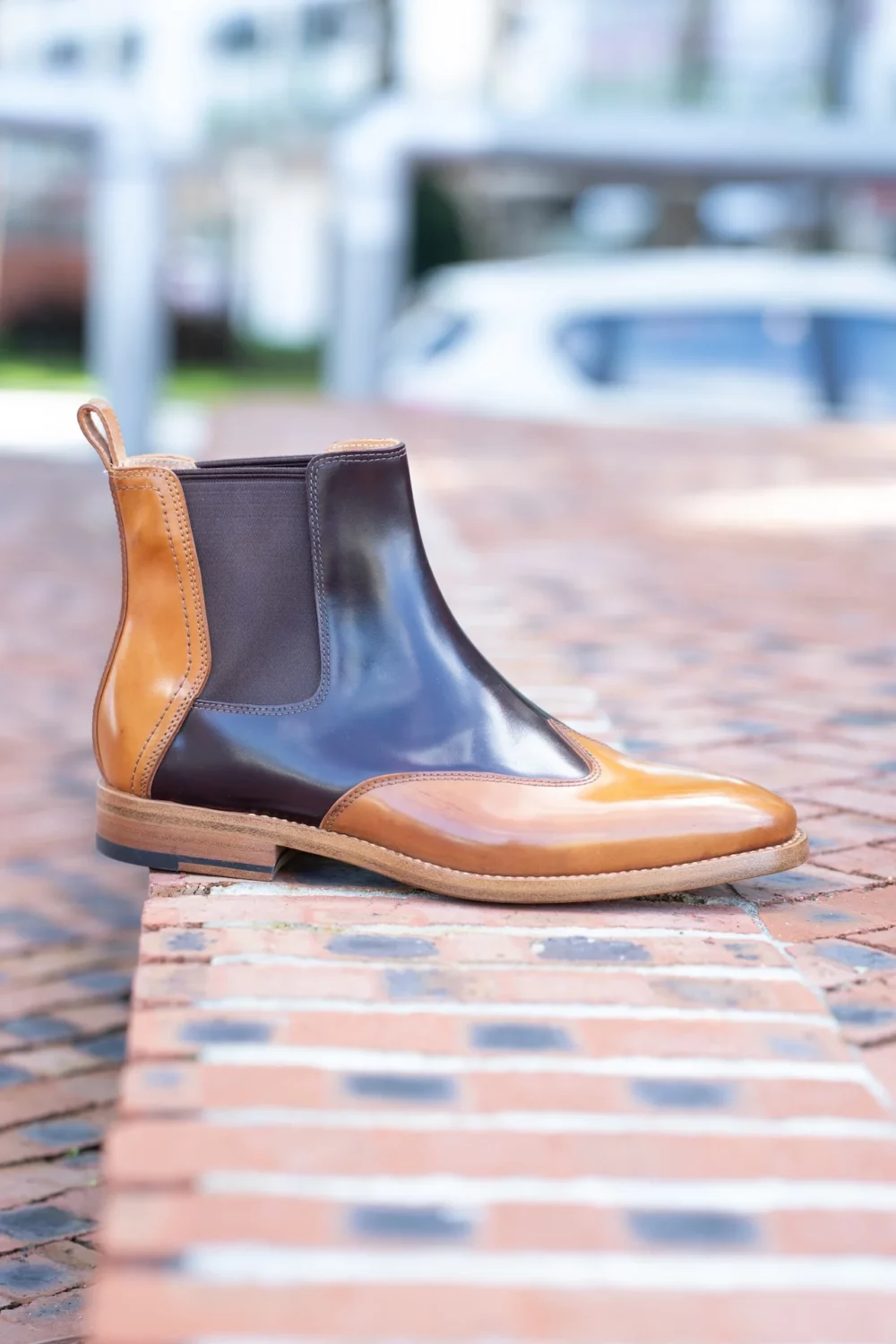 A stylish brown and tan leather Chelsea boot with a rounded toe and elastic side panels.