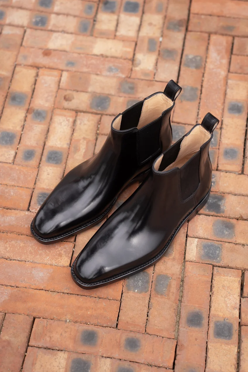 A pair of polished black leather Chelsea boots with a sleek design.