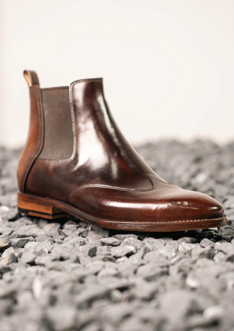 A brown cordovan Chelsea boot with a shiny finish and elastic side panels.
