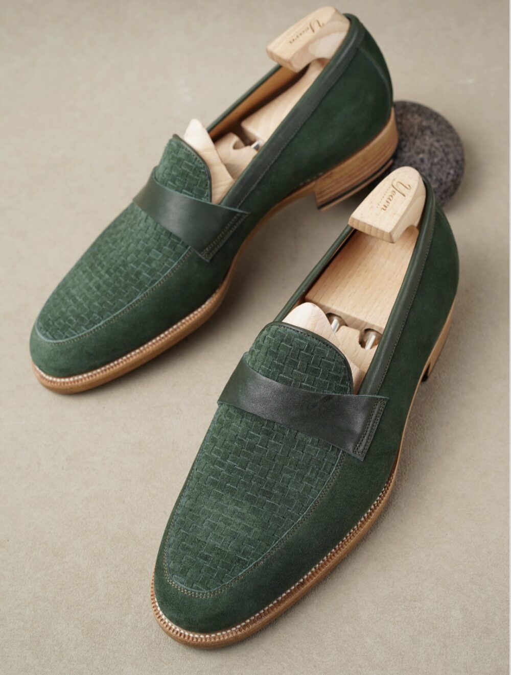 Two green suede Amalfi loafers with a woven texture and leather strap across the top.