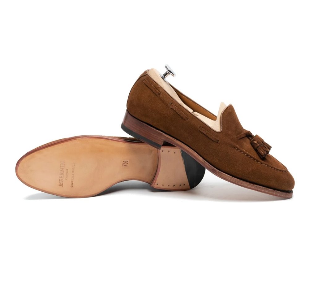 Brown suede loafers with a tassel detail and a leather sole.