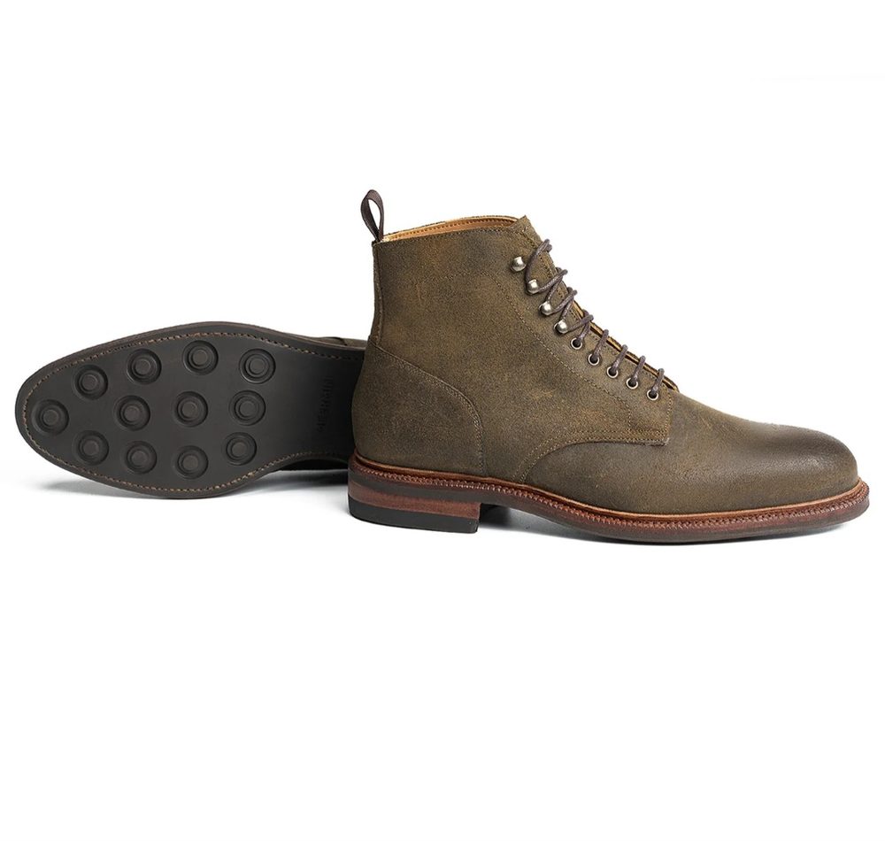 A pair of brown leather ankle boots with a rubber sole and metal eyelets.