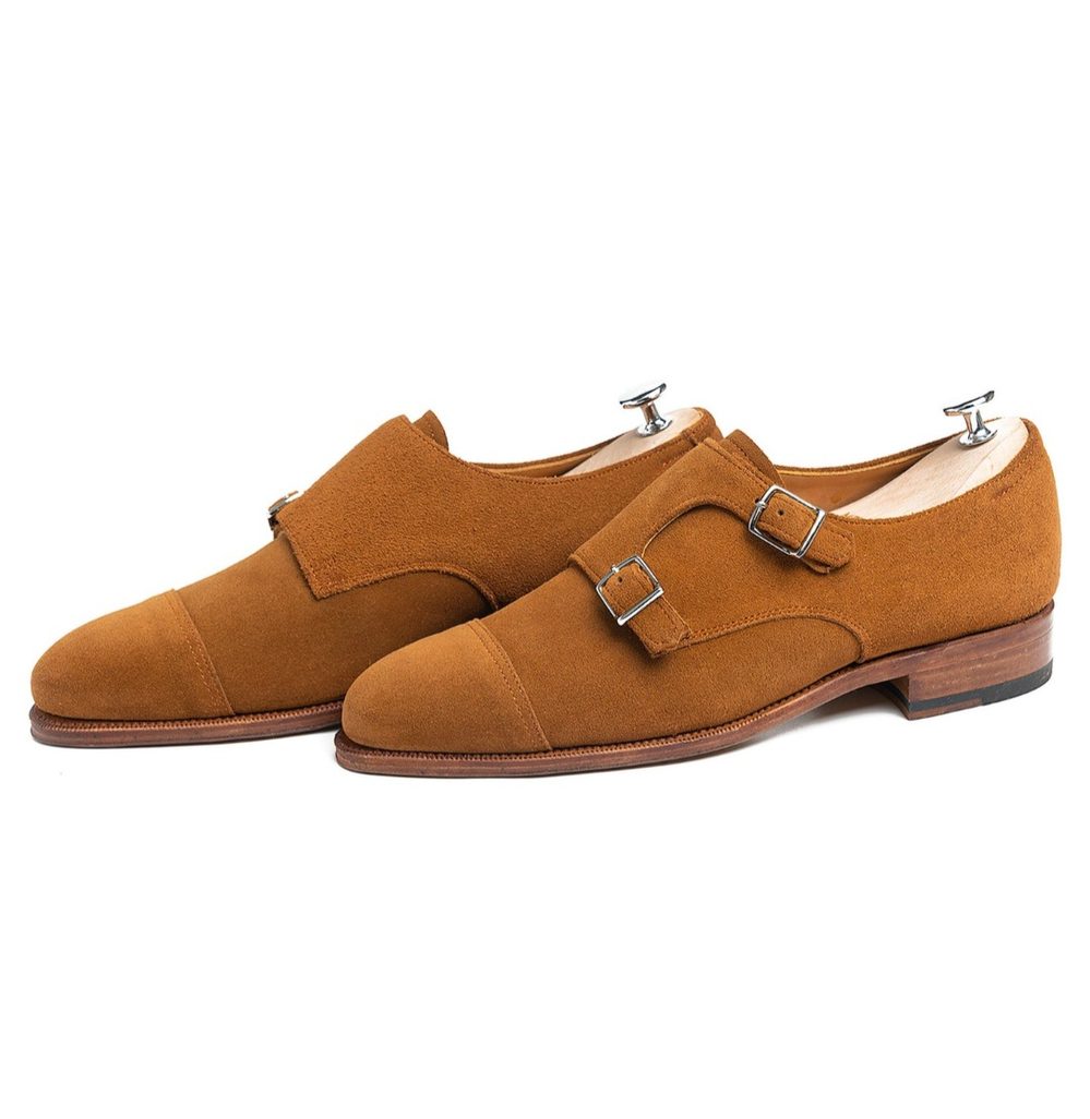 A pair of brown suede double-monk strap shoes with silver buckles.