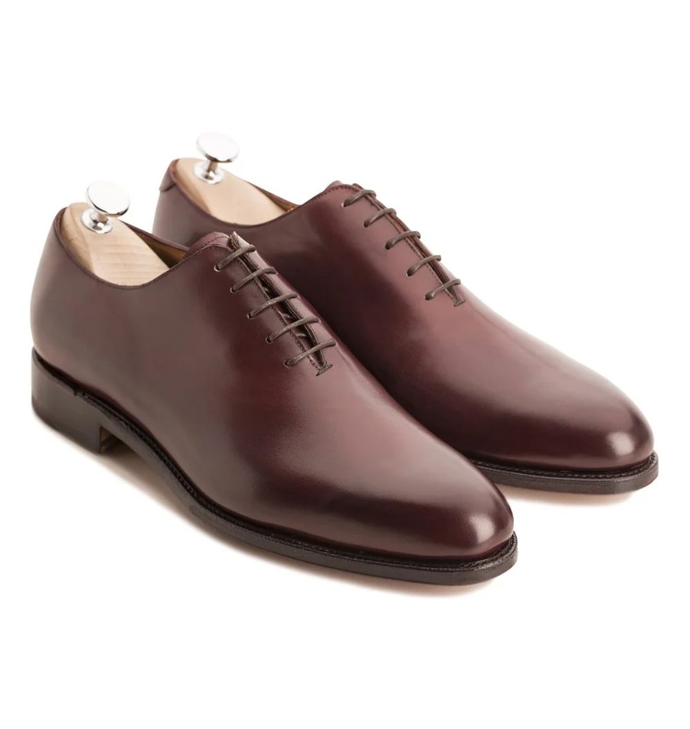 A pair of burgundy leather dress shoes with a sleek design and laces.