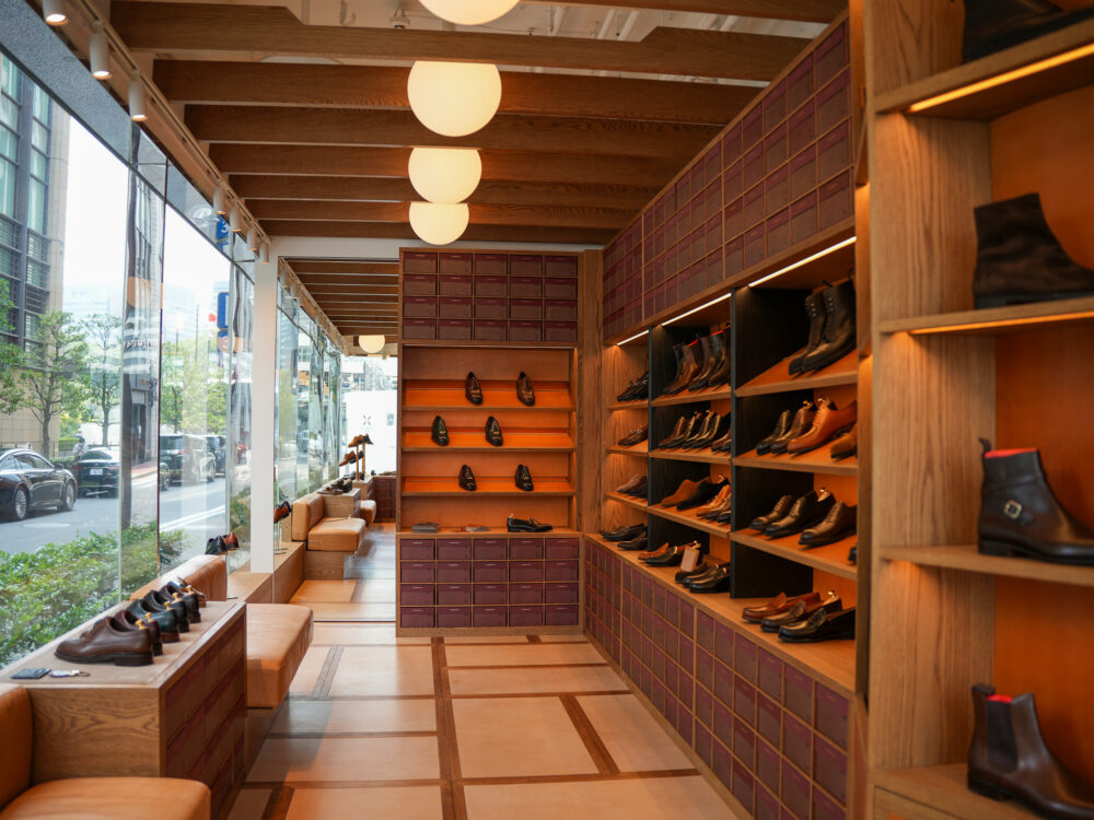 Interior of a shoe store featuring wooden shelves displaying various styles of leather footwear in shades of brown and black.
