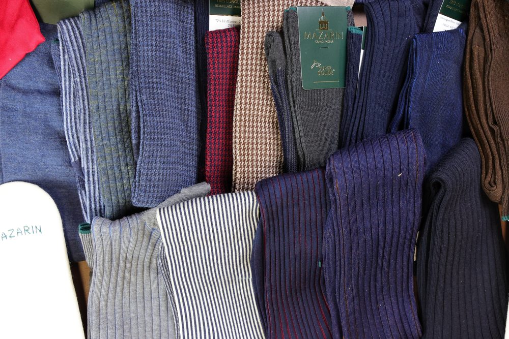 A collection of various socks in shades of blue, gray, burgundy, and patterned designs.