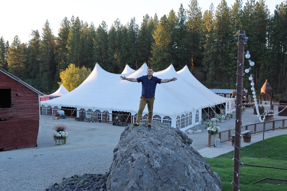 A person in a blue shirt stands on a rock with arms outstretched, in front of a large white tent, symbolizing "My New Chapter."