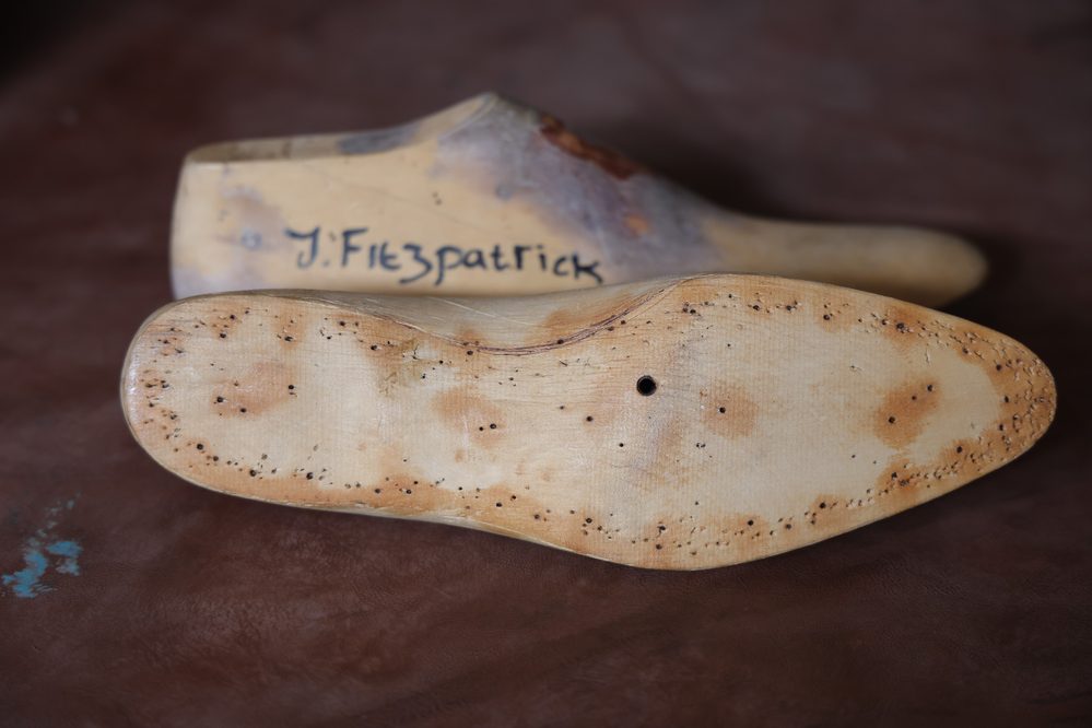 A wooden shoe last with a curved shape and visible markings, illustrating what is a shoe last.