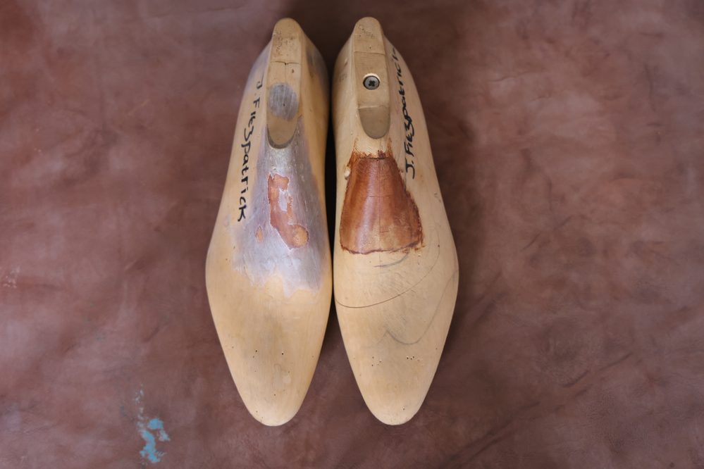 Two wooden shoe lasts, one showing wear and a patch, labeled with "J. F. Spatrick," illustrating what is a shoe last.