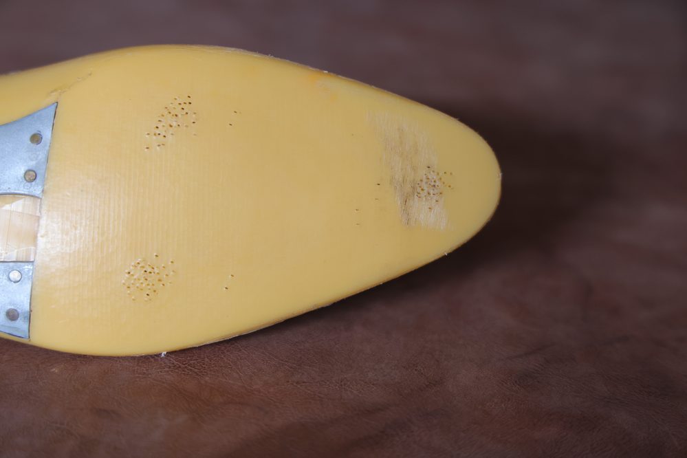 A close-up of a yellow shoe last showing its textured surface and metal components, illustrating what is a shoe last.