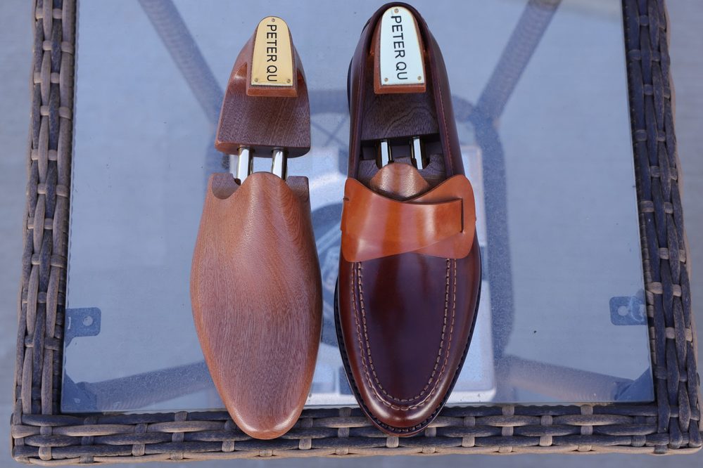 A pair of stylish brown leather shoes with a wooden shoe tree, showcasing different shades of brown.