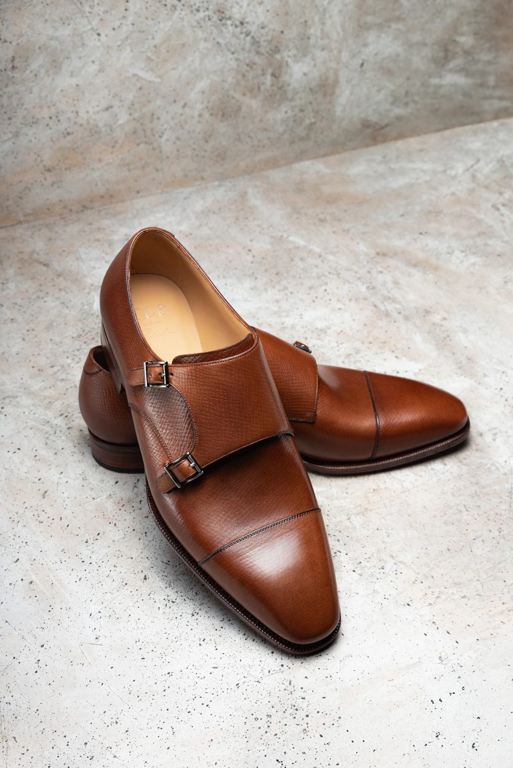 A pair of brown leather dress shoes with double buckles and pointed toes.