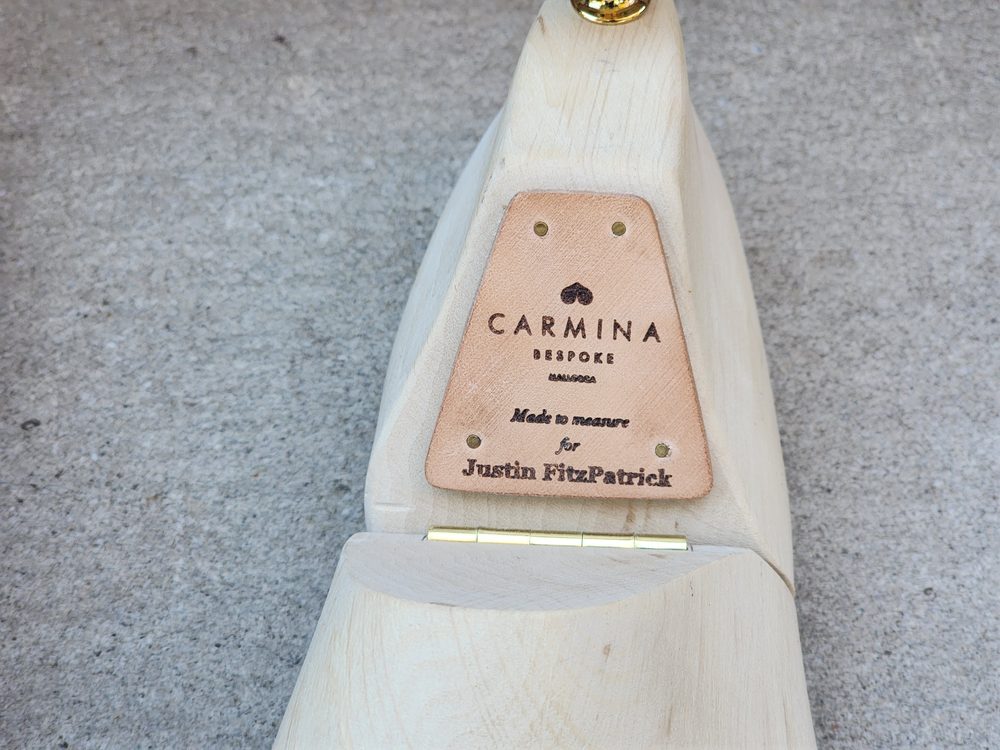 A wooden shoe tree with a leather tag reading "Carmina Bespoke" and "Made to measure for Justin FitzPatrick."