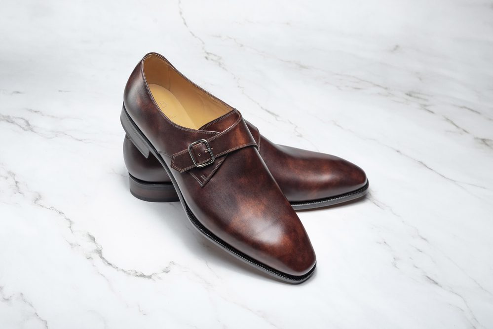 A pair of brown leather dress shoes with a buckle detail.