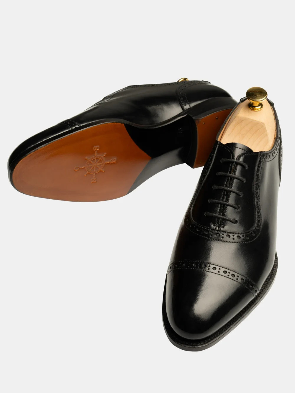 Black leather dress shoes with brogue detailing and wooden shoe trees.