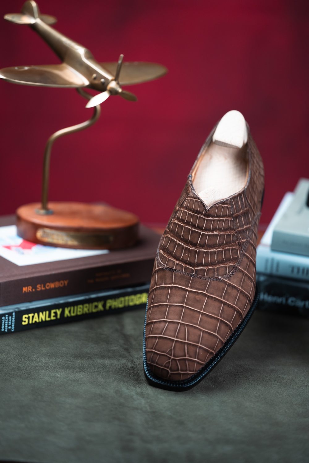 A brown crocodile nubuck shoe with a pointed toe and sleek design.
