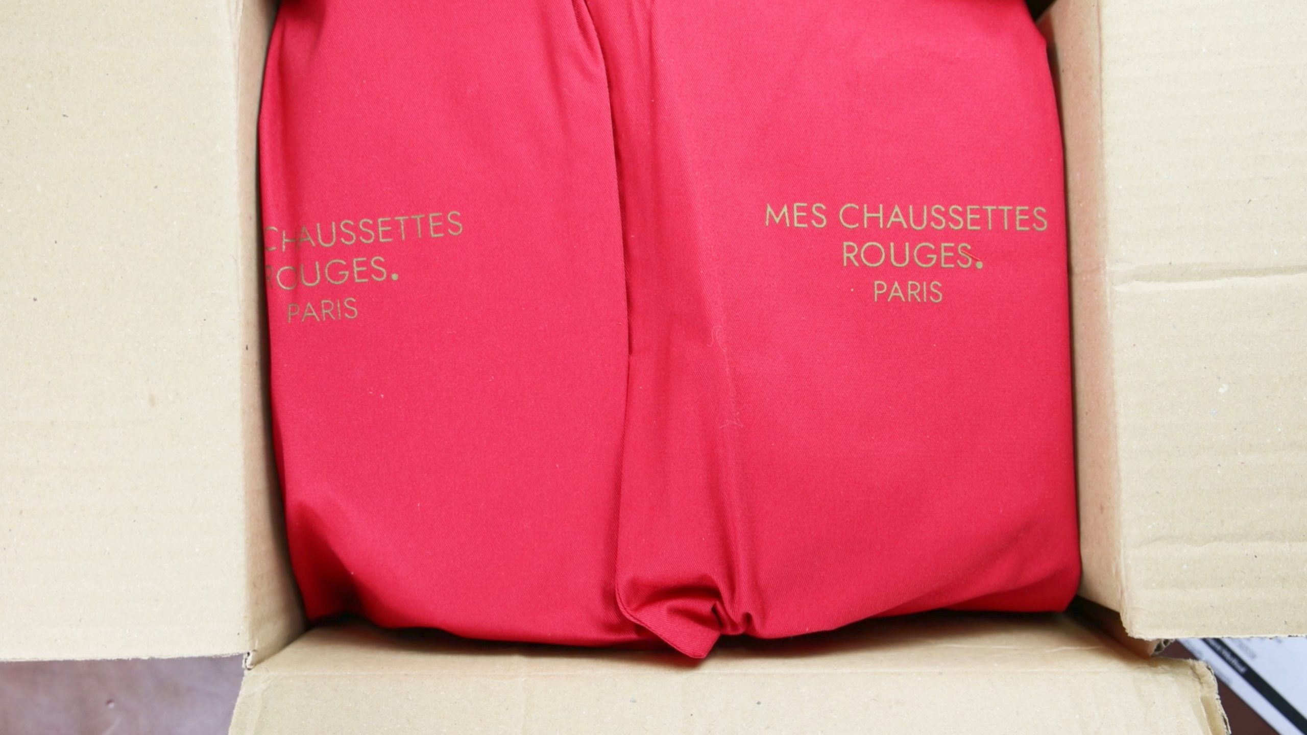 Two red packages with "Mes Chaussettes Rouges. Paris" printed in gold.