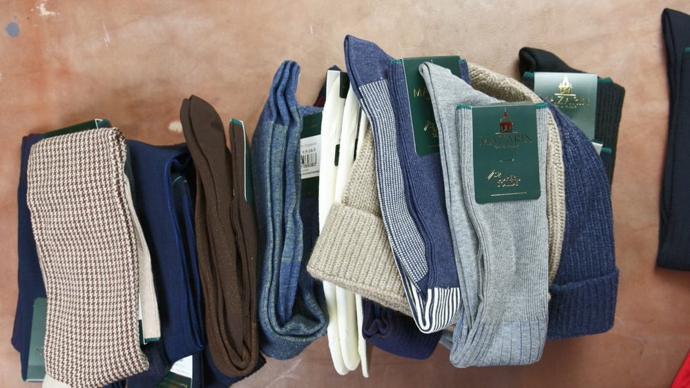 A collection of colorful socks in various shades, including blue, brown, gray, and cream, with tags visible.