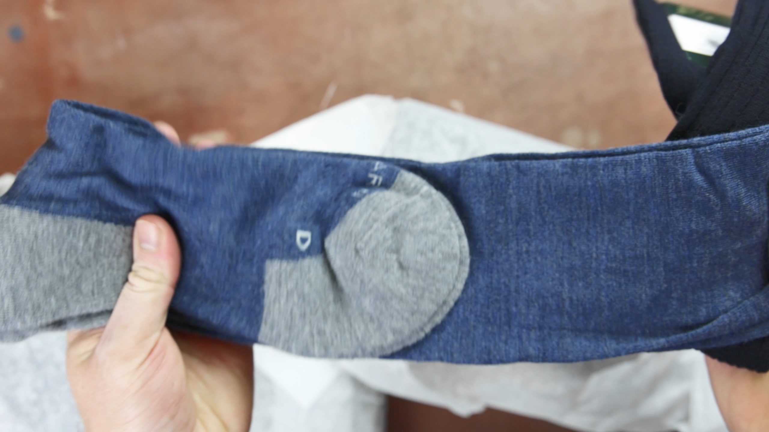 A person holds a pair of blue socks with a gray heel and toe.