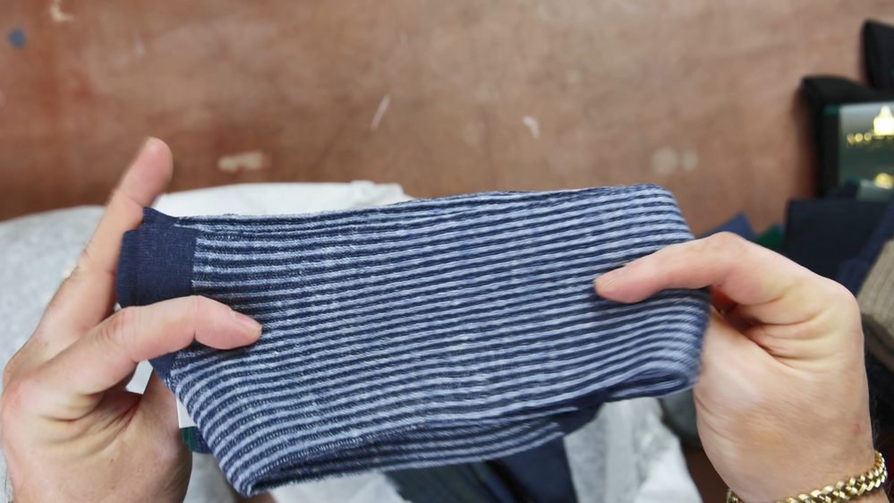 A person holds a navy blue and white striped sock.