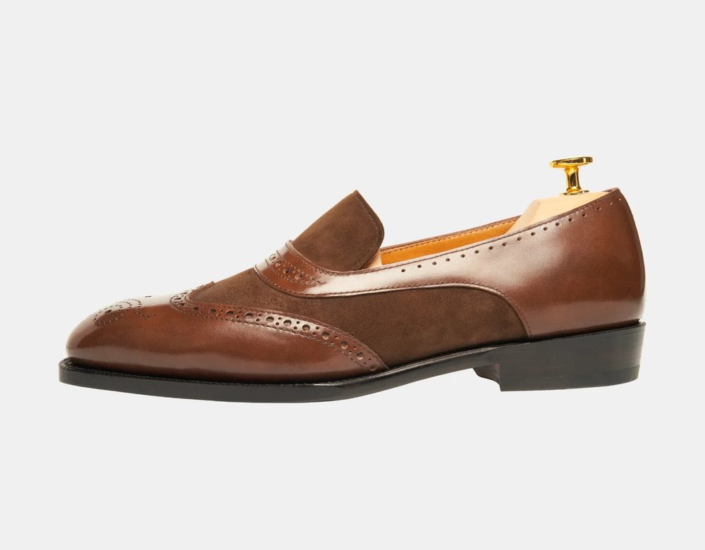 A brown leather shoe featuring a combination of smooth and nubuck textures with decorative perforations.