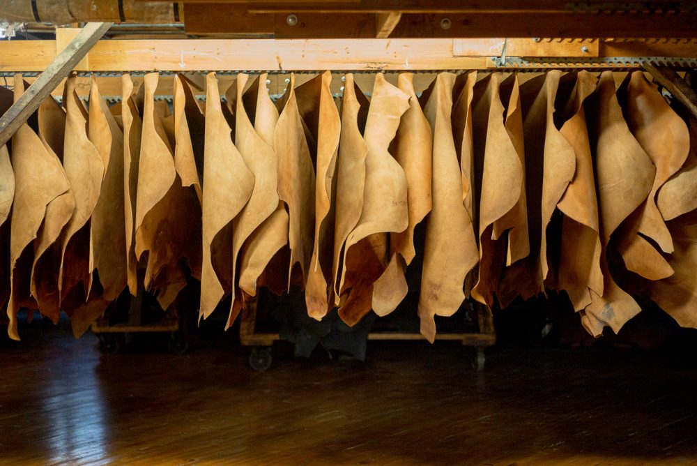 Hanging pieces of light brown leather are displayed for the Carmina Bespoke Trunk Show.