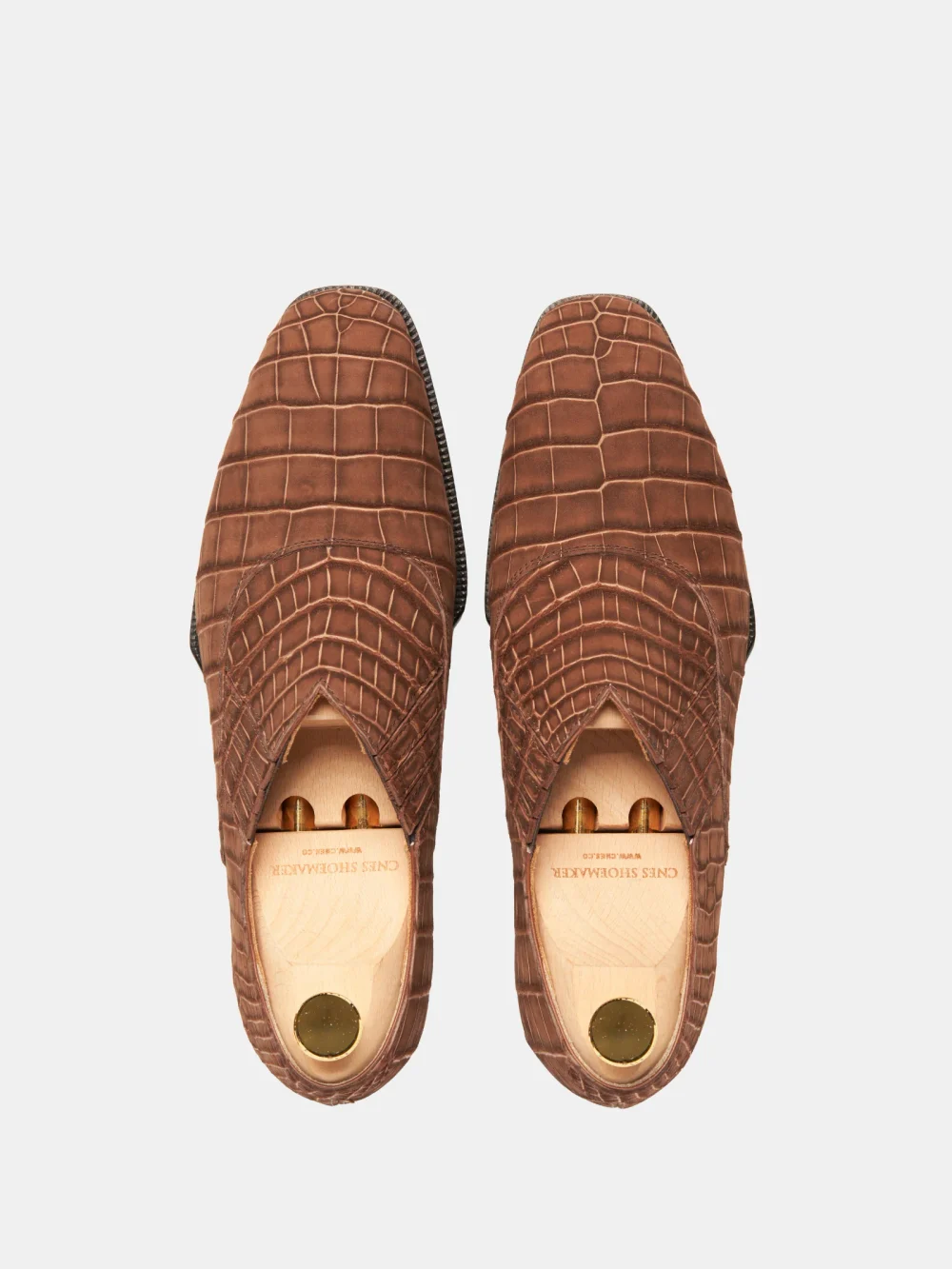 Brown crocodile nubuck shoes with a textured surface and open toe design.