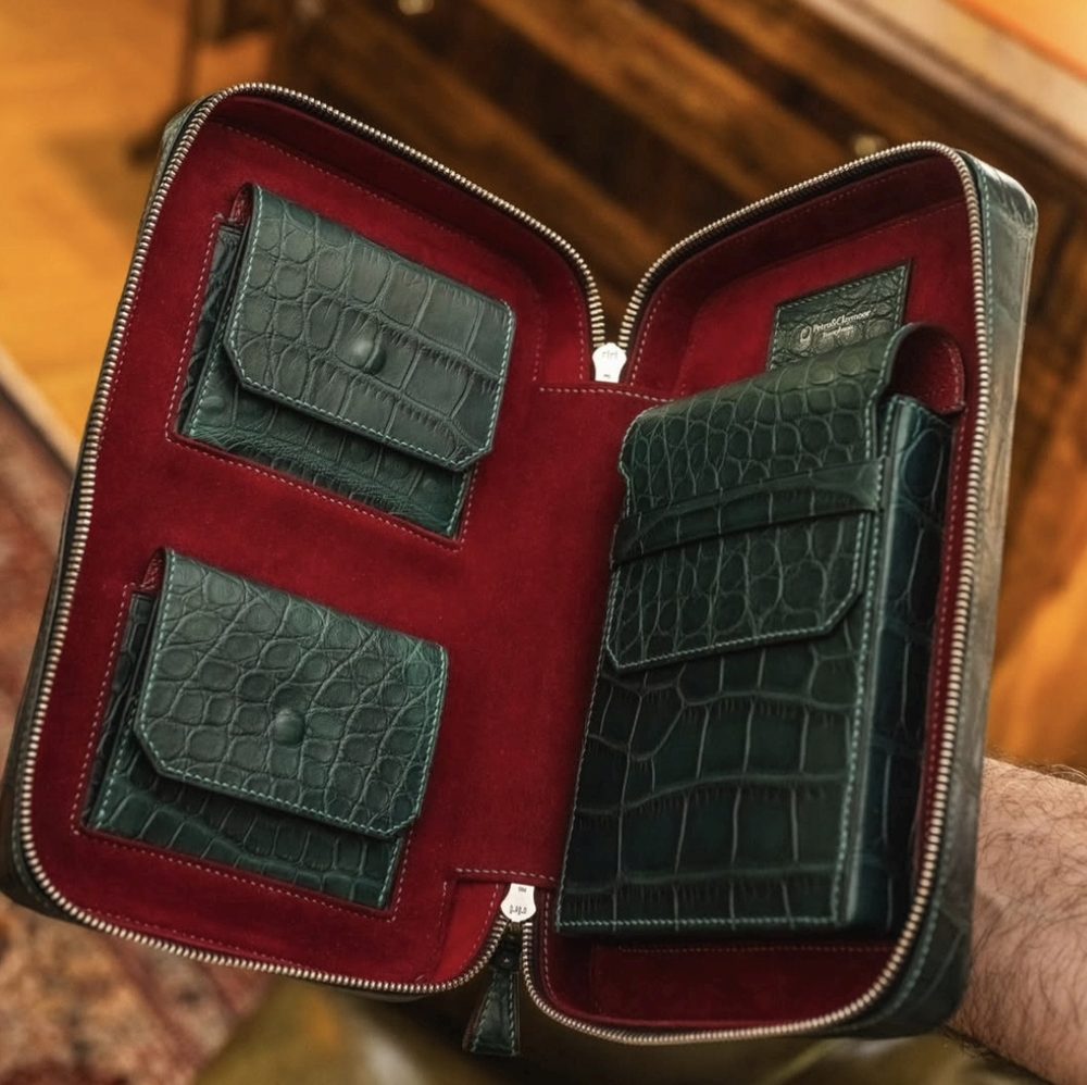 A zipped case with multiple green crocodile leather card holders on a red interior.
