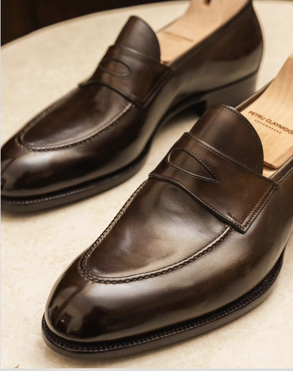 A pair of polished brown leather loafers with a decorative strap detail.