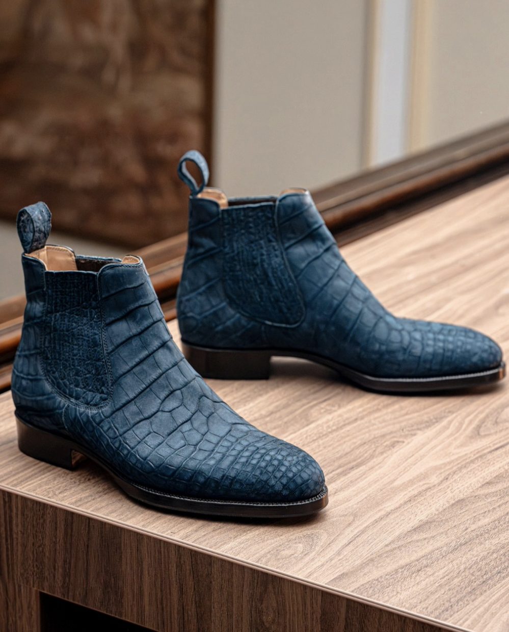 A pair of handmade blue crocodile leather ankle boots with a low heel.