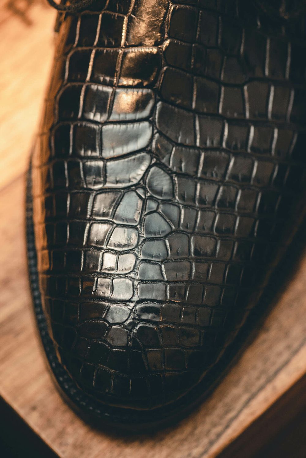 Close-up of a black crocodile leather shoe showcasing its textured surface.