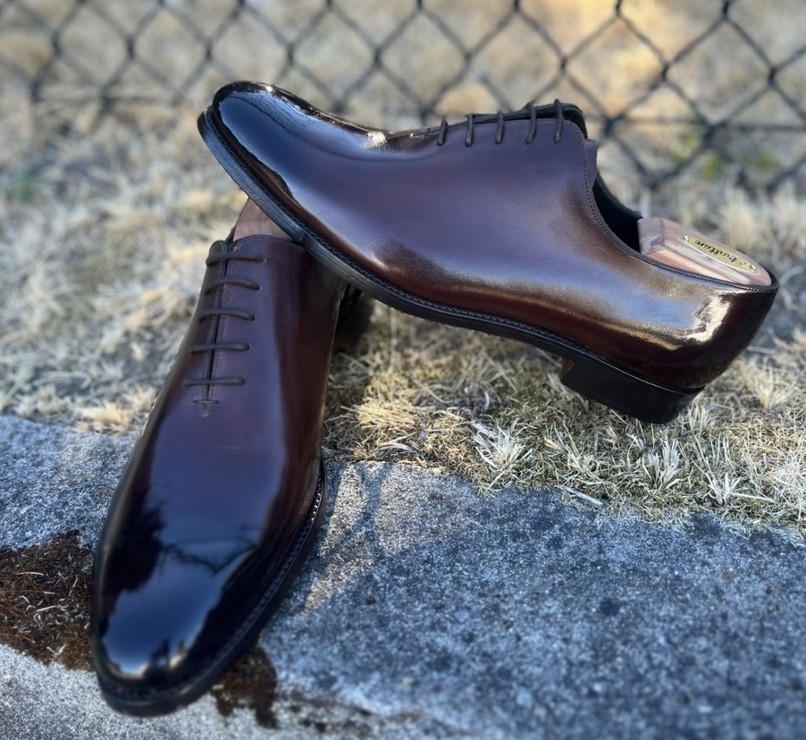 A pair of polished brown leather dress shoes with laces.