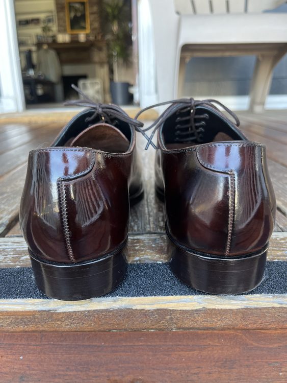A close-up view of polished burgundy dress shoes, showing the back and laces.
