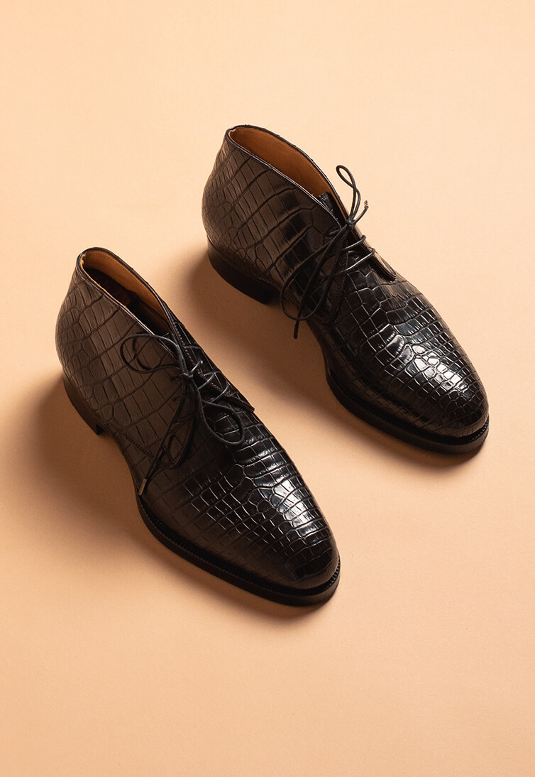 Black crocodile leather shoes with a pointed toe and lace-up design.
