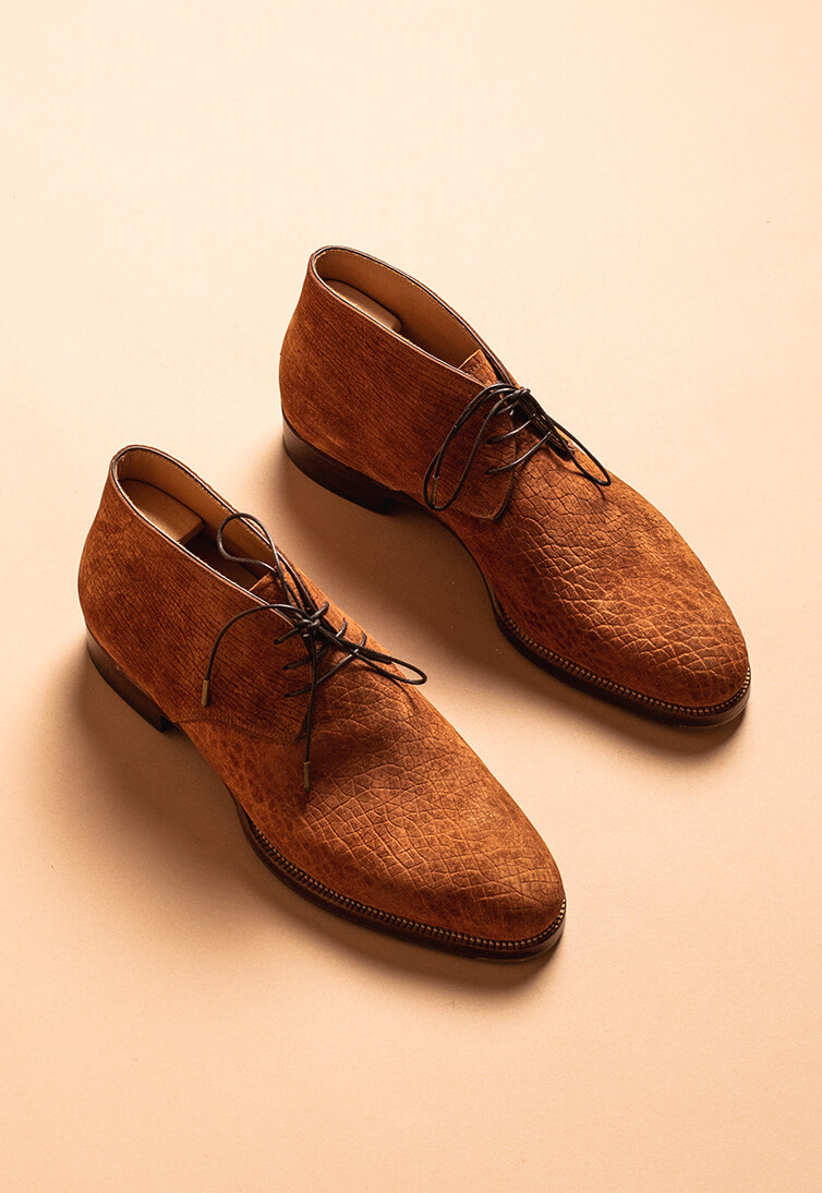 Brown handmade shoes with a textured leather finish and black laces.