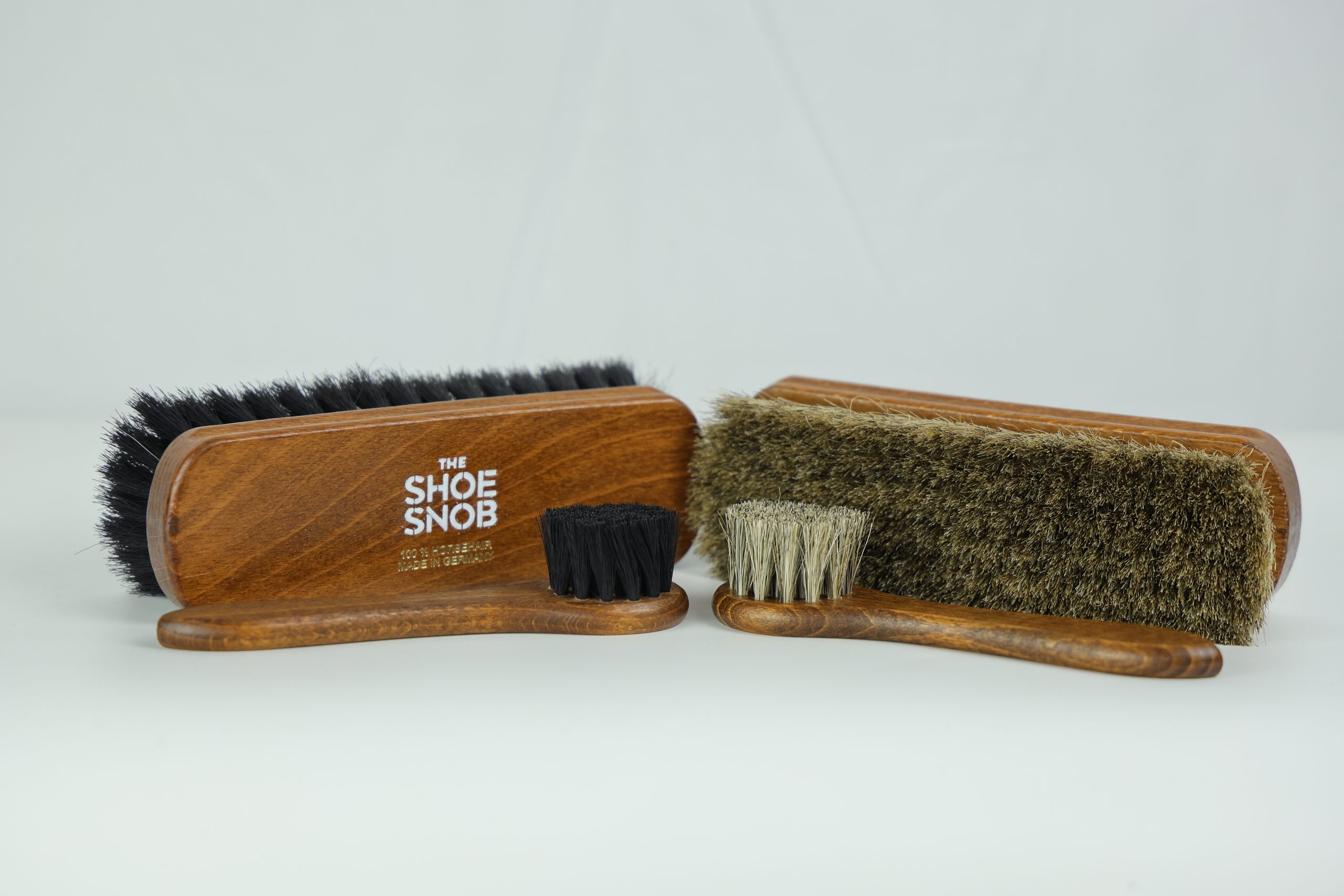 Two wooden shoe brushes, one with black bristles and the other with tan bristles, featured in the shoe care guide.