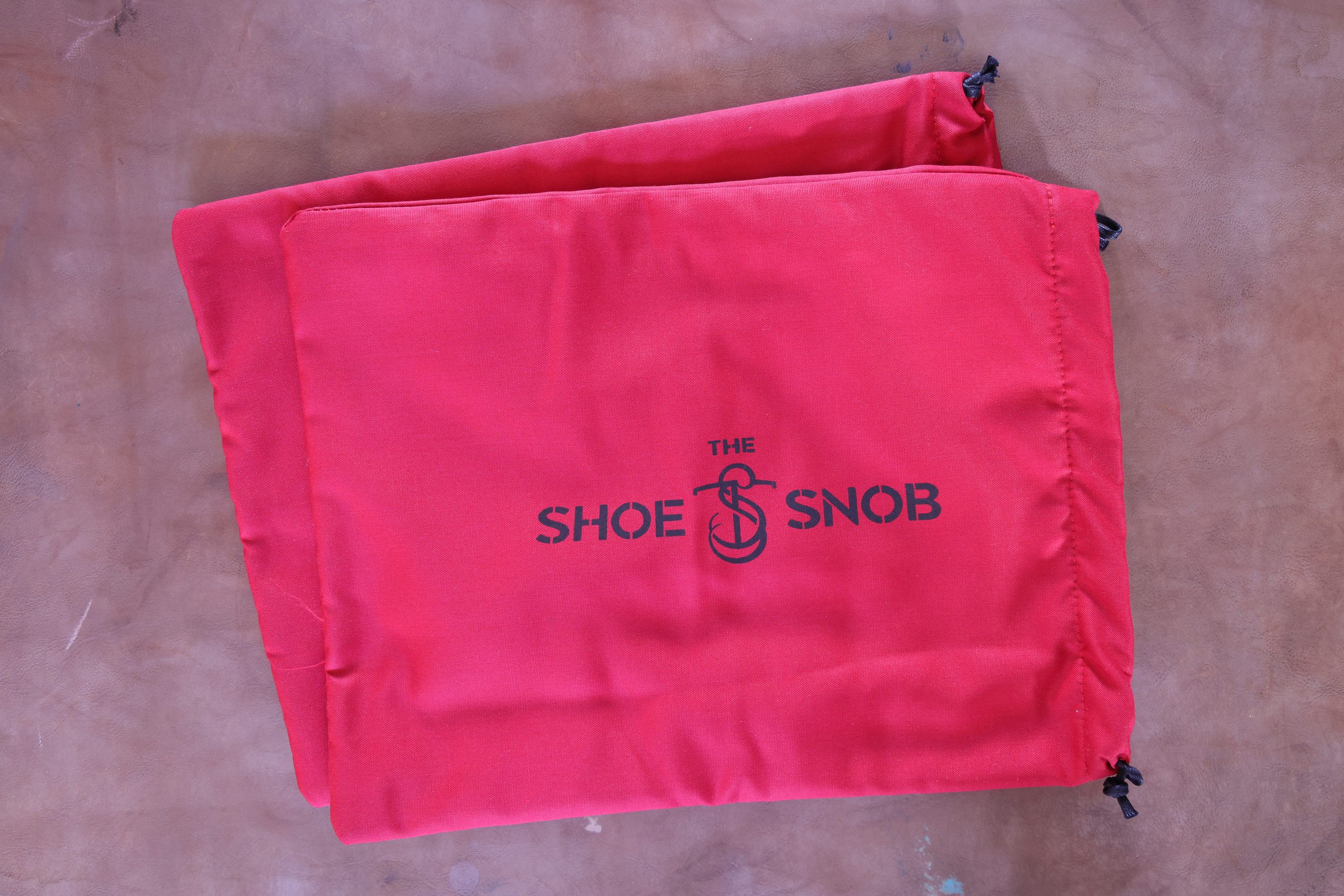 Red shoe bags with the text "THE SHOE SNOB" for how to properly store dress shoes.