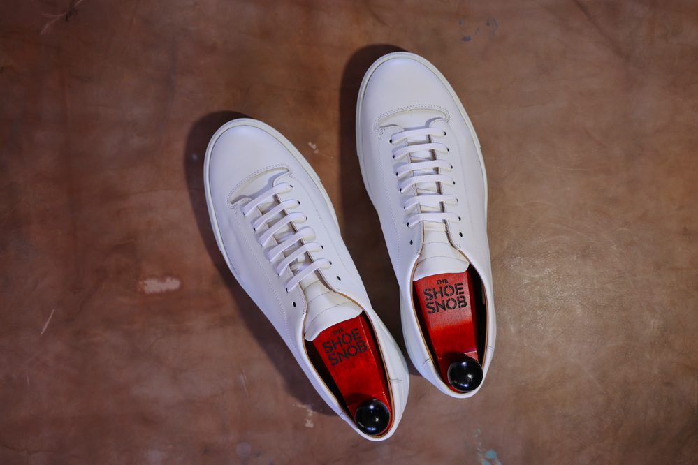 A pair of white dress shoes with wooden shoe trees inside, illustrating how to properly store dress shoes.