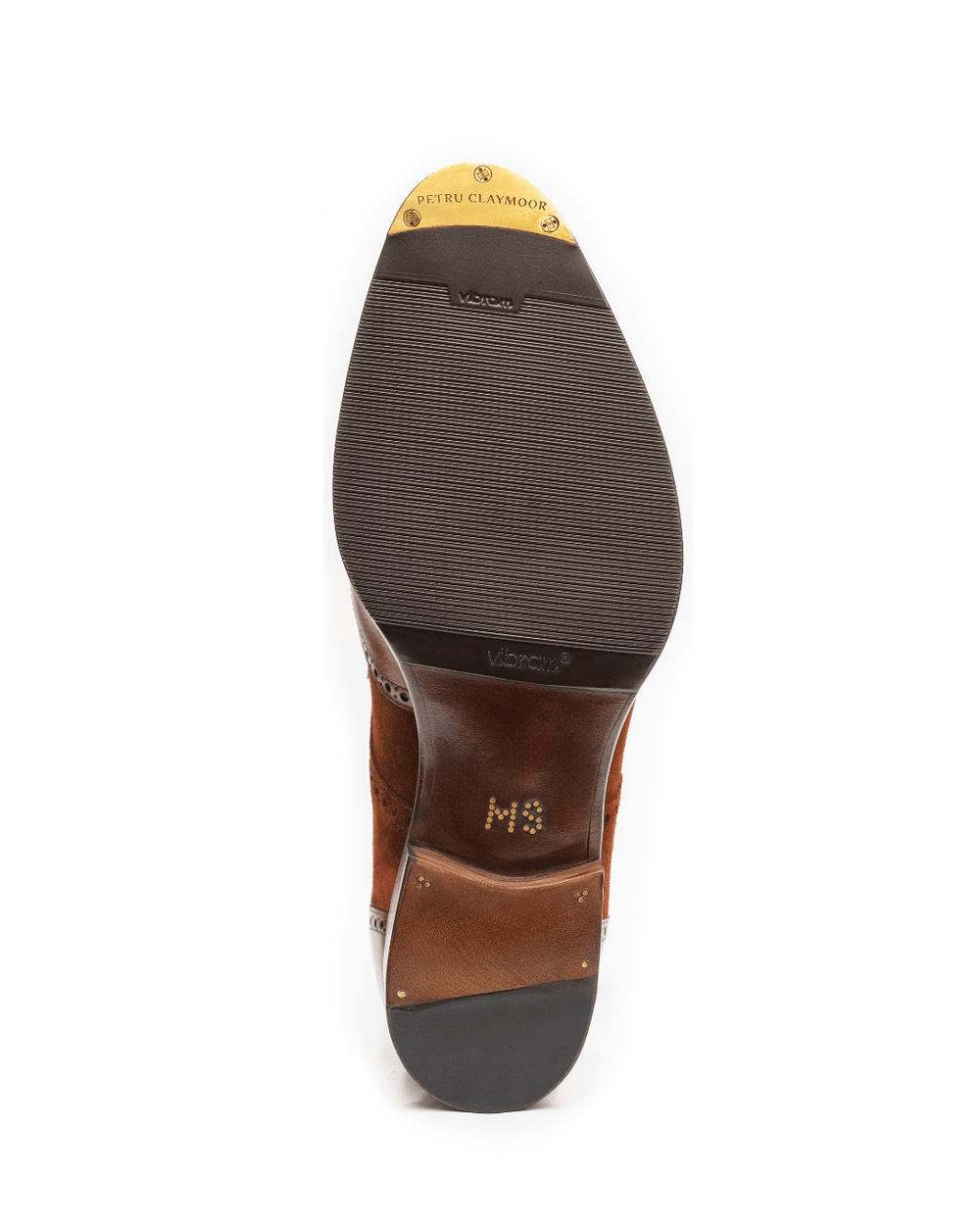 The image shows the sole of a brown suede shoe with a gold logo and a Vibram label.