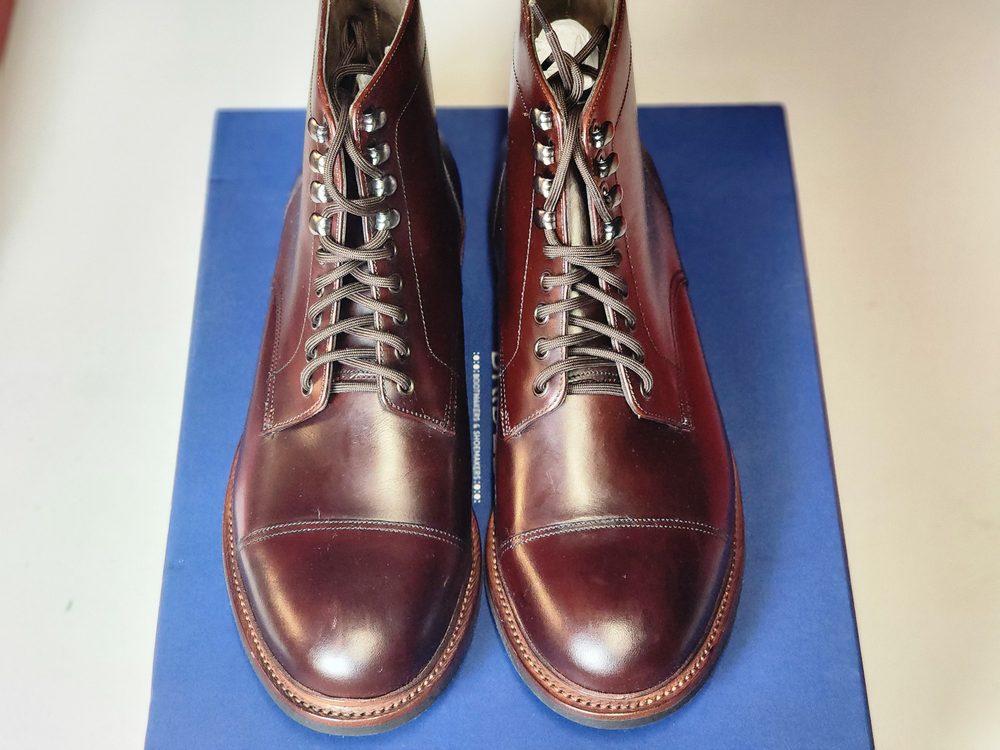 A pair of polished burgundy shoes with lace-up detailing sits on a blue surface.