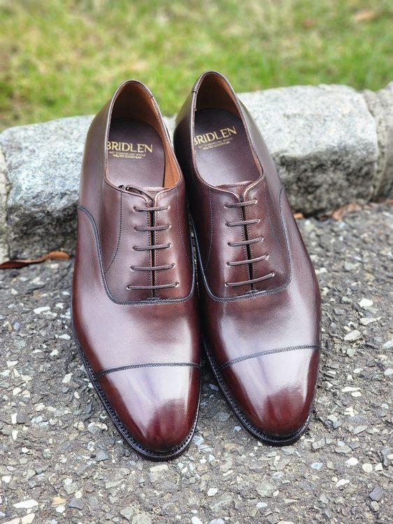 A pair of polished brown leather Oxford shoes with a sleek design and detailed stitching, featured in the context of "Oxford vs wingtip."