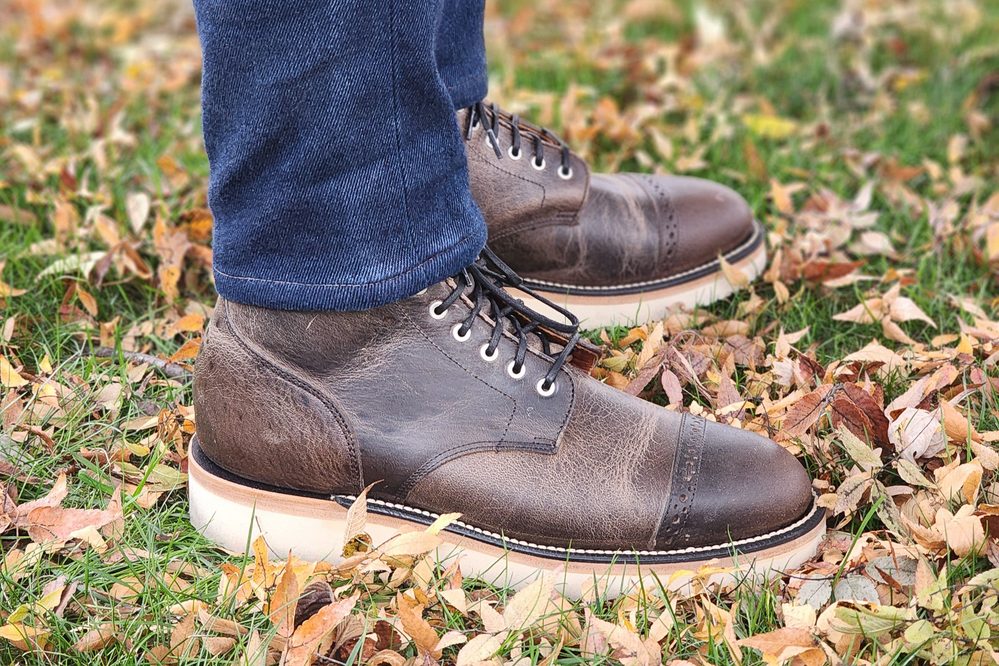 A close-up of Grant Stone brown leather boots with white soles, worn with dark jeans