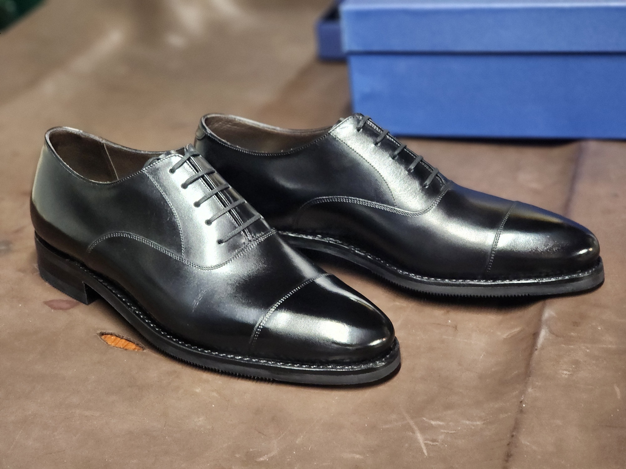 A pair of shiny black leather Oxford shoes with a sleek design and closed lacing, featured in the "Oxford vs wingtip" discussion.